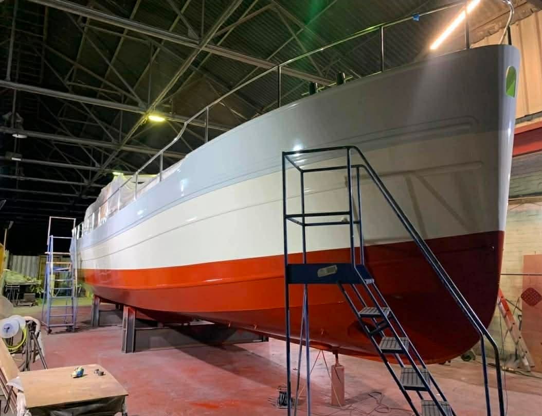 The river cruiser after spraying, with white and cream topsides and a red hull below the waterline