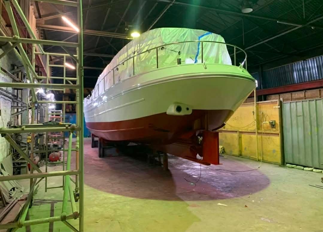 Stern view of the finished river cruiser in gloss white with its superstructure still sheeted